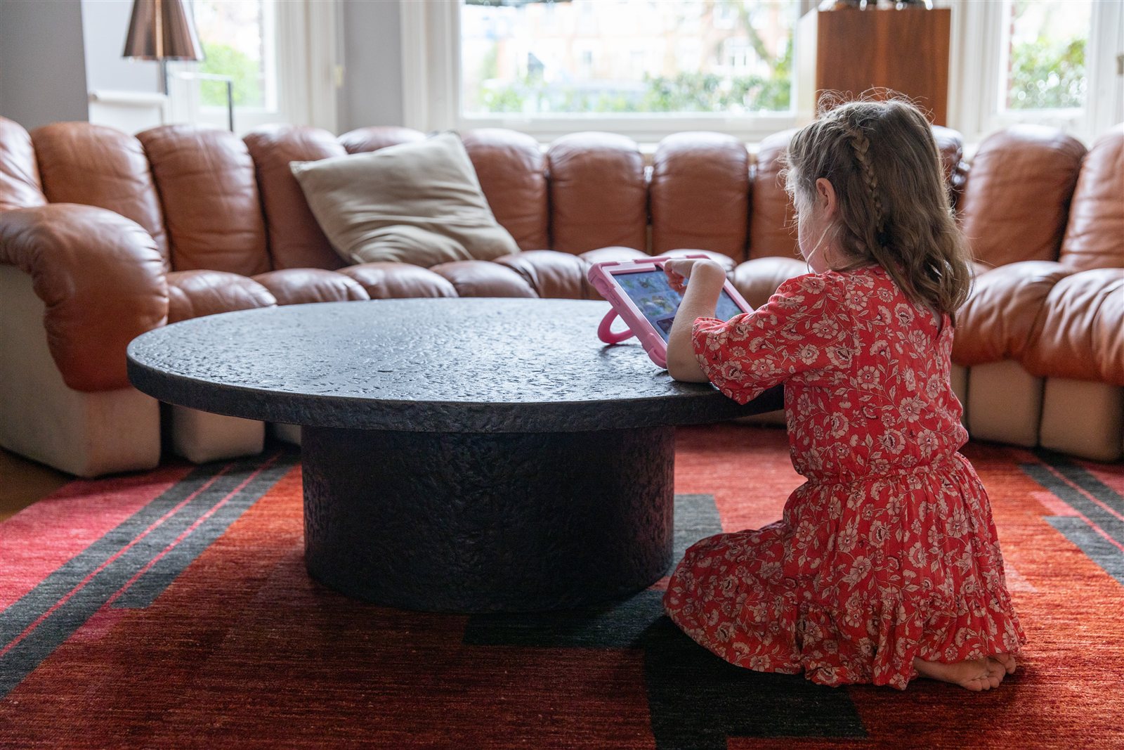 Een kind van achteren aan de salontafel met een roze kinder-iPad