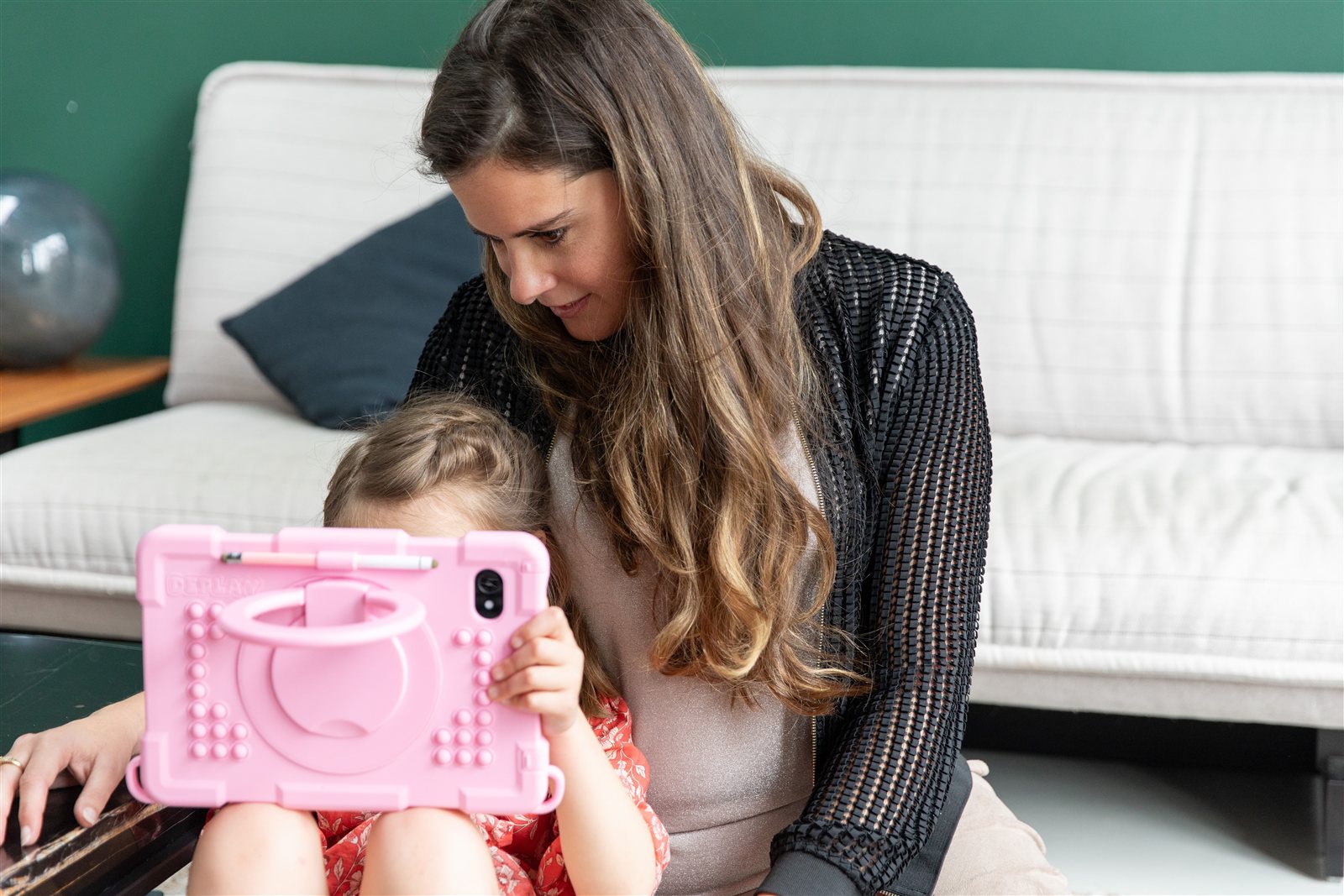 Een kind achter een roze kinder-iPad, Lisanne kijkt mee